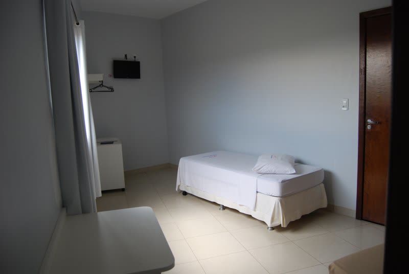 Quarto com cama, televisão na parede e janela